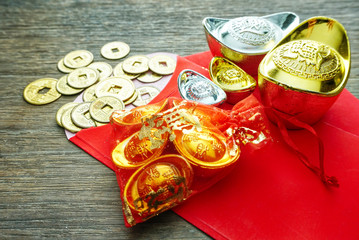 Gold bar and silver and coins decorate with red envelope on wood table for chinese new year theme