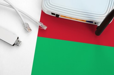 Madagascar flag depicted on table with internet rj45 cable, wireless usb wifi adapter and router....