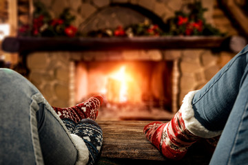 Fototapeta na wymiar Desk of free space and people legs with christmas socks.Home interior with fireplace and 