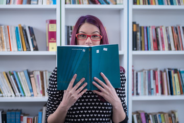 Young female student posing, reading and learning in library