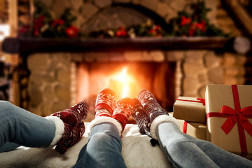 Desk of free space and people legs with christmas socks.Home interior with fireplace and 
