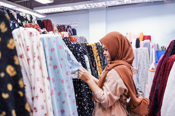 Muslim woman pick a roll of cloth at the fabric mall, They sell Muslim fashion online and in-store in retail.