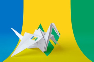 Saint Vincent and the Grenadines flag depicted on paper origami crane wing. Handmade arts concept