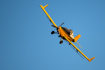 Yellow Crop Dusting Plane Flying in a Blue Sky