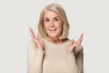 Head shot of surprised elderly woman showing sincere amazement emotions