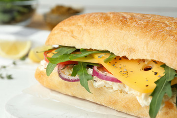 Delicious sandwich with fresh vegetables and cheese on white table, closeup