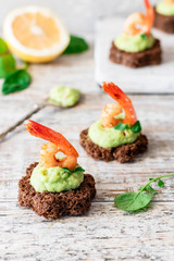 Canapes with avocado mousse and spicy shrimp on brown bread