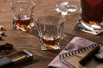 Glasses of brandy, cigars with map and pistachios on wooden table