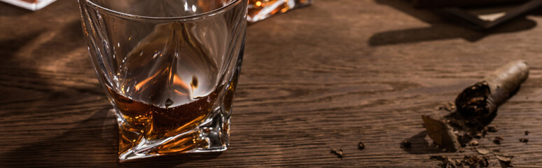 Brandy in glass with cigar on wooden table, panoramic shot