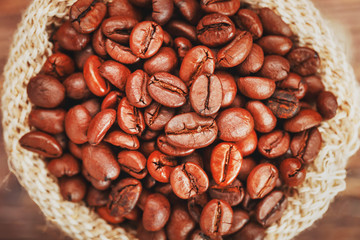 Coffee beans in a burlap bag on a wooden background. Soft contrast Aromatic roasted coffee beans.