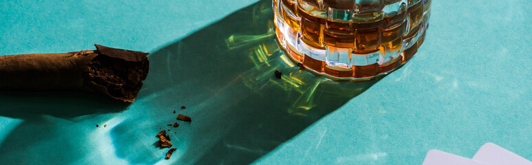 Panoramic shot of glass on brandy with cigar on green background