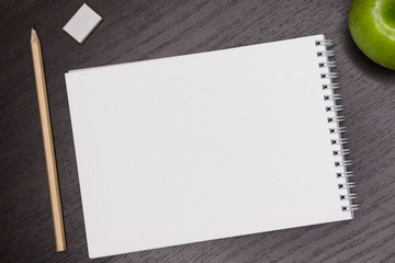 Top view. Mock up. Blank white sheet on a dark background for notes. Dark wooden background.