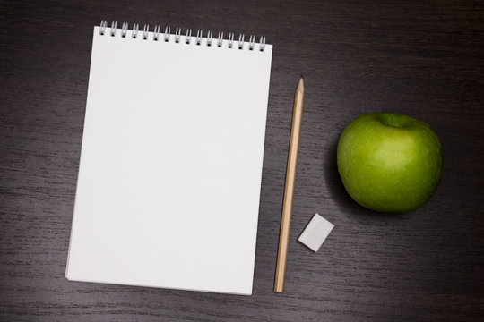 Mock up for school, university, study, writer or artist. clean notebook. With green apple. Dark wooden background.