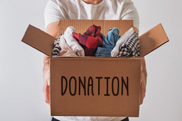 Close-up shot of man holding donation box with clothes