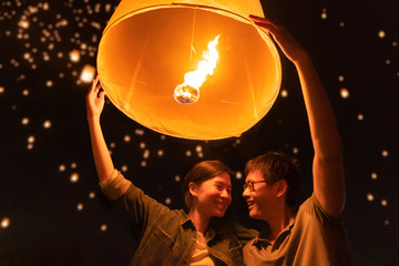 A couple release sky floating lanterns or lamp to worship Buddha's relics at night. Traditional...