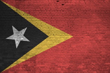 Timor Leste flag depicted in paint colors on old brick wall. Textured banner on big brick wall...