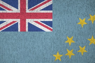 Tuvalu flag depicted in bright paint colors on old relief plastering wall. Textured banner on rough...