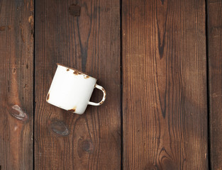 white metal mug with rust on a brown wooden background