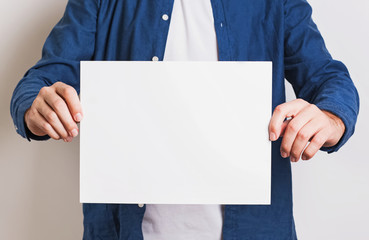 Man in blue shirt holding white blank paper