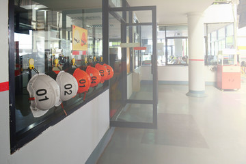 the orange and white safety  helmets hanging on glass wall near the door in the factory