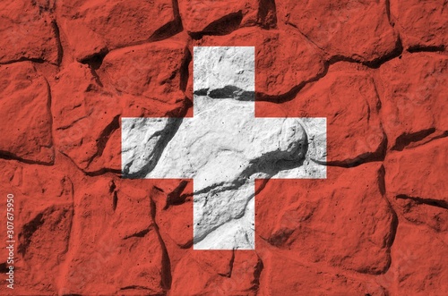 Switzerland flag depicted in paint colors on old stone wall closeup. Textured banner on rock wall background