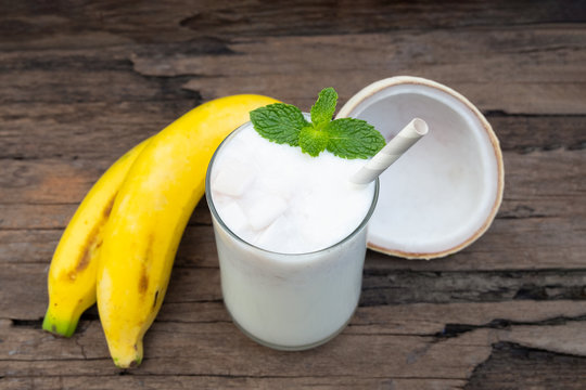 Coconut blend banana milk smoothie drink fresh cocktail shake milkshake vanilla juice fruit beverage food healthy the taste yummy In glass on wooden background.