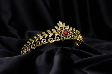 golden crown with rubies  on a black silk
