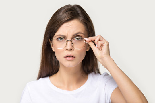 Skeptic millennial brunette woman lower glasses as sign of confusion