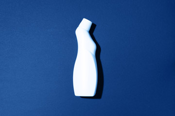 White plastic bottle of cleaning product, household chemicals or liquid laundry detergent on classic blue background. Top view. Flat lay. Copy space. Detergent bottle