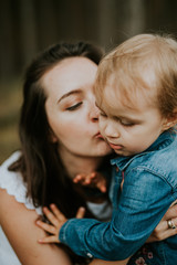 Happy mother and daughter in the park. Beauty nature scene with family outdoor lifestyle. Happy family resting together on the green grass, authentic lifestyle image.
