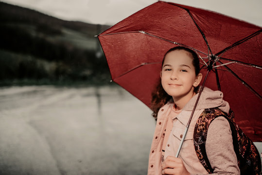 Little girl waiting for bus on rain day