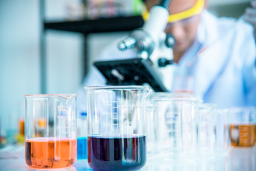 Test tubes and solution beakers in a science laboratory with a multicolored liquid on the laboratory table for a chemical background Concept Search