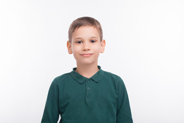 Portrait of happy boy standing over white background and looking confident at the camera