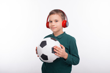 Young boy holding soccer ball and wearing red headphones