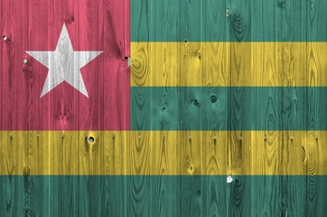 Togo flag depicted in bright paint colors on old wooden wall. Textured banner on rough background