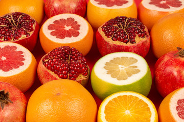 Grapefruit, orange, pomegranate, citrus sweetie on red background.