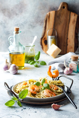 Italian pasta spaghetti with grilled shrimps, pesto sauce and fresh basil leaves