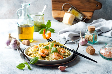 Italian pasta spaghetti with grilled shrimps, pesto sauce and fresh basil leaves