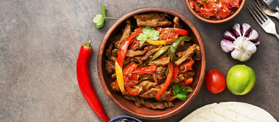 Traditional mexican dish fajitas meat with vegetables and salsa sauce, banner. View from above.