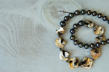 A necklace of pearl beads and pearls on a blue wooden surface, feminine jewelry, jewelry, close-up,...