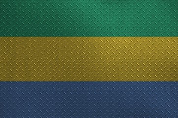 Gabon flag depicted in paint colors on old brushed metal plate or wall closeup. Textured banner on...