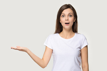 Excited millennial woman shocked holding her hand for copyspace