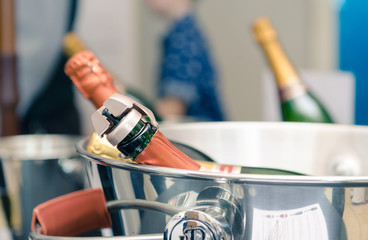 A champagne cork fizz stopper in the top of expensive champagne bottle in an ice bucket. Keeping...