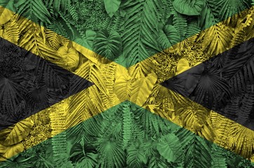 Jamaica flag depicted on many leafs of monstera palm trees. Trendy fashionable backdrop