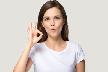 Fototapeta premium Headshot of happy young woman showing OK sign