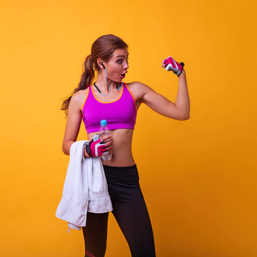 Image of a beautful young amazing sports fitness african woman posing showing display of mobile phone showing biceps.Healthy beautiful sportswoman wearing tracksuit with towel looking aside 