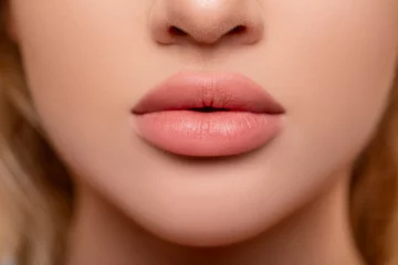 Fotobehang Beautiful lips Close-up. Makeup. Lip matte lipstick. Sexy lips. Part of face, young woman close up. advertisement. perfect plump lips bodily lipstick. peach color of lipstick on large lips.  © Julia