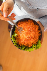 Carrot salad. Woman holds a bowl with carrot salad. Vegan and vegetarian food.