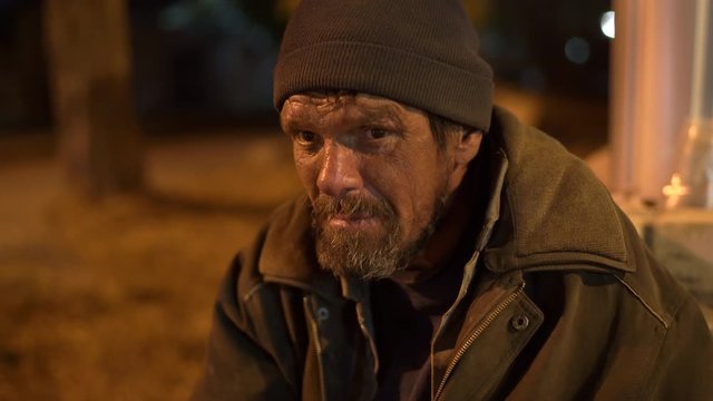Face of lonely cold homeless man on the street at night.