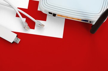 Tonga flag depicted on table with internet rj45 cable, wireless usb wifi adapter and router....